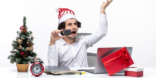 holiday-festive-mood-with-young-tired-angry-business-person-with-santa-claus-hat-holding-his-bank-card-office-white-background_600x300
